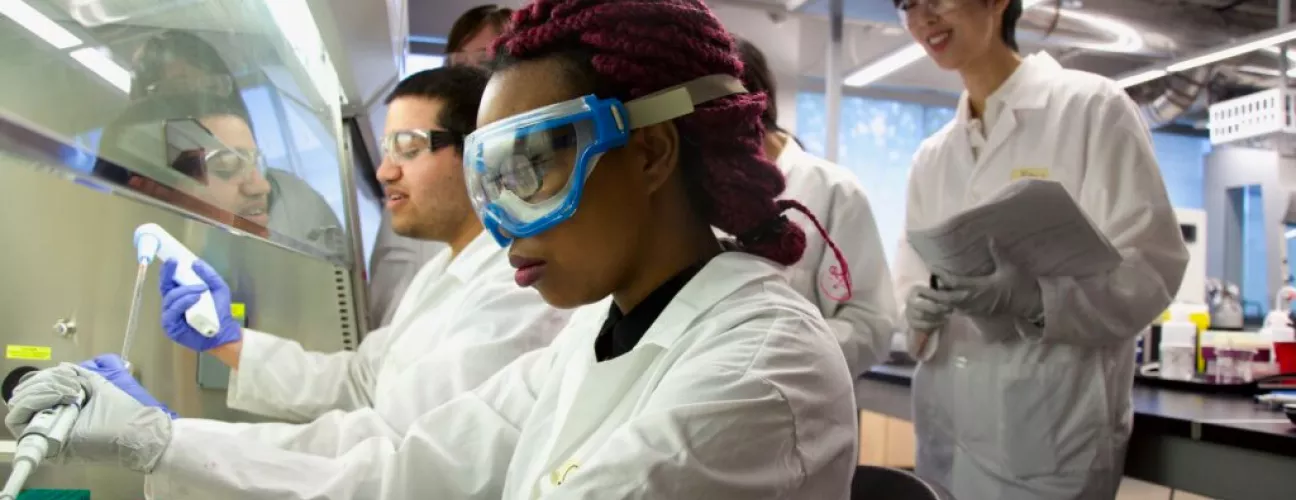 Students wearing safety goggles using chemicals