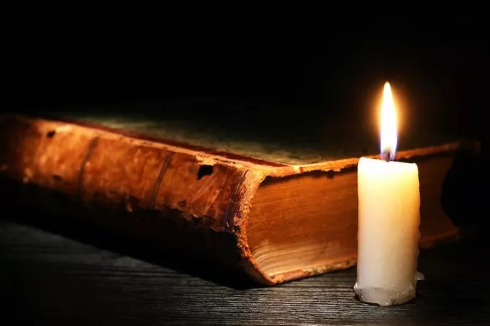 Photo of an antique book and short white candle with flame - from Shutterstock