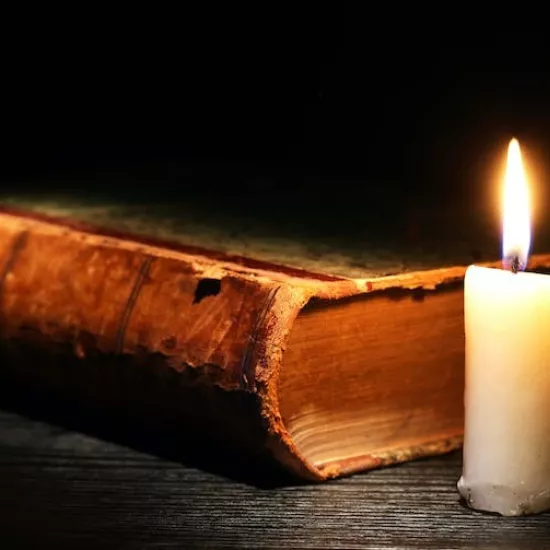 Photo of an antique book and short white candle with flame - from Shutterstock
