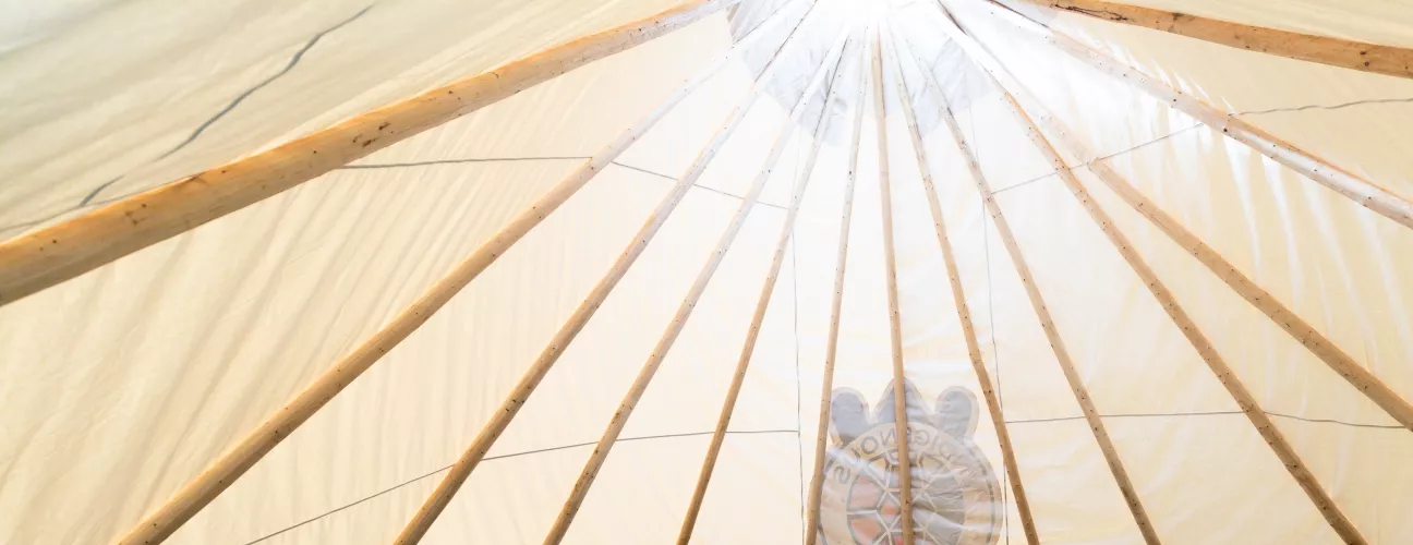 A low shot of the inside of UTM's tipi with a gathering of people