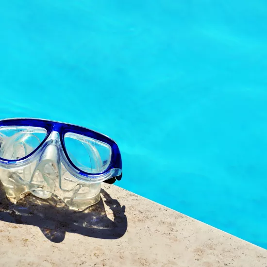 Blue framed swimming goggles near pool at daytime