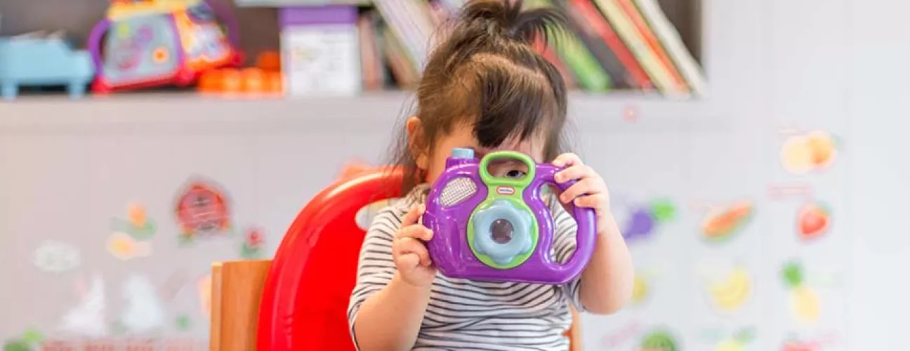 Toddler girl playing with a toy in daycare setting. Photo by Tanaphong Toochinda on Unsplash