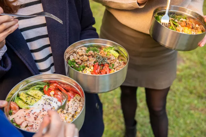 people hold waste-free metal takeout containers in a park
