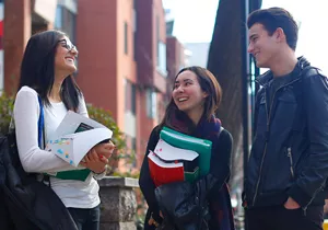 three students standing together and laughing
