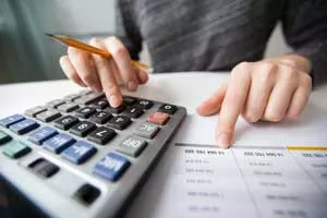 Closeup photo of financial spreadsheets and hands using a calculator and 