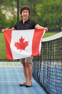 Alison Dias on a tennis court holding a Canadian flag