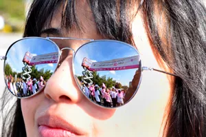 Run for the Cure banner and balloons reflected in woman's sunglasses