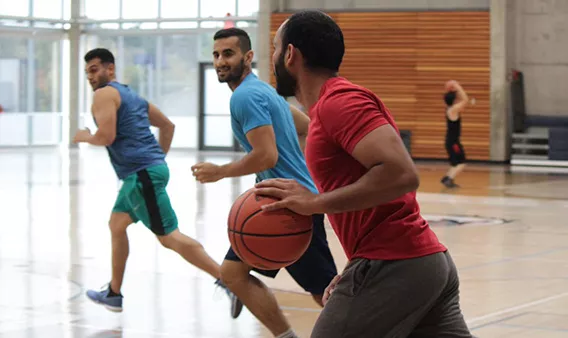 Three men playing basketball in a gym