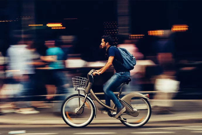 A man bikes along a busy city street.