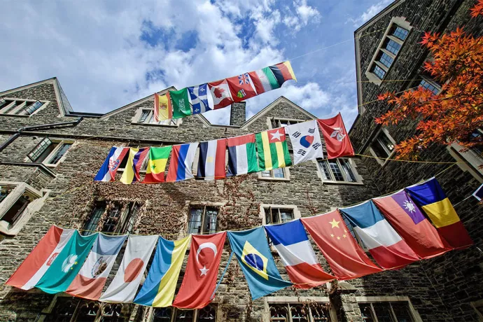 Photo of various country flags handing outside a stone building