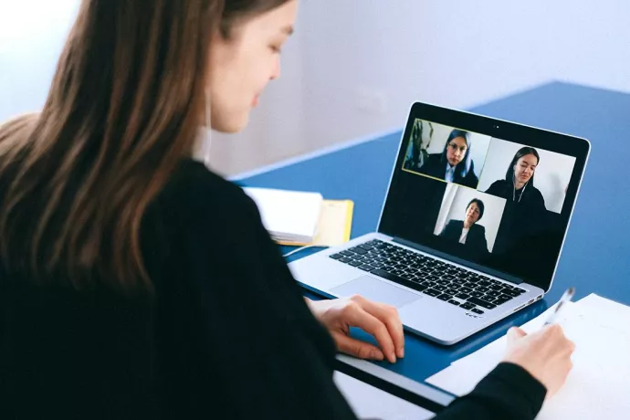 Woman in front of laptop on video call with three others shown on screen