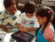Three children gathered around, looking at a tablet.