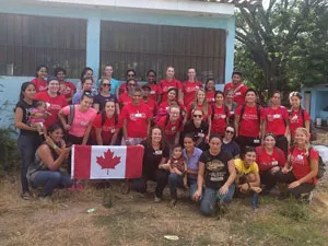 Students wearing red t-shirts hold a Canadian flag