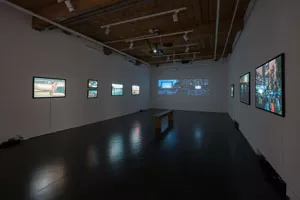 Photograph of a darkened art gallery with light boxes on the walls.