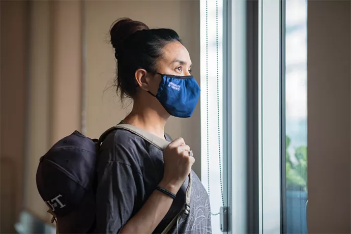 Woman wearing blue mask with University of Toronto written on it