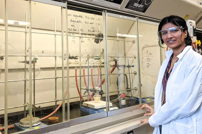 Avneet in lab coat in front of lab equipment