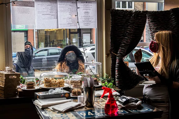 Sasha Steinberg serving a woman wearing a parka standing at the window to the restaurant
