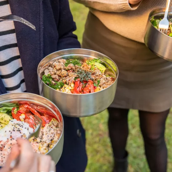 people hold waste-free metal takeout containers in a park