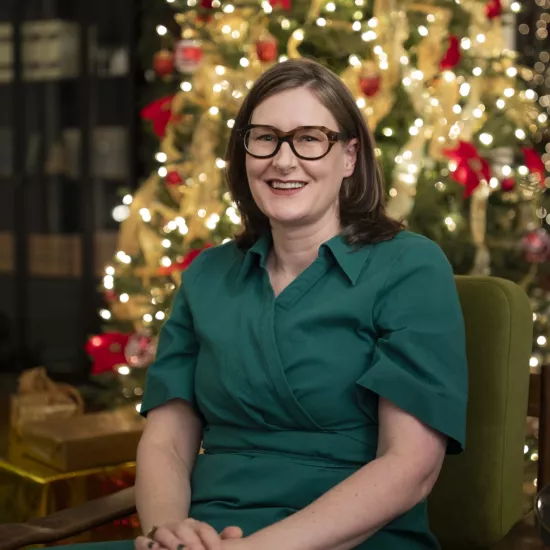Alexandra Gillespie sits in front of a festively decorated Christmas tree. 