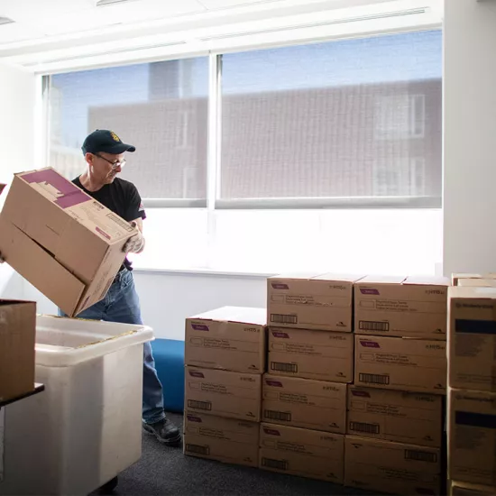Man moving a box in a room filled with neatly stacked boxes