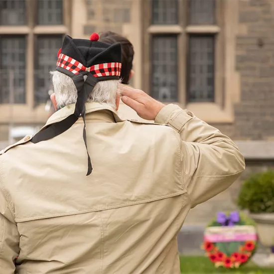 Veteran with back to the camera, standing and saluting. Wreaths seen in the background