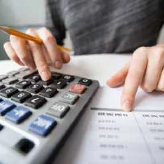 Closeup photo of financial spreadsheets and hands using a calculator and 