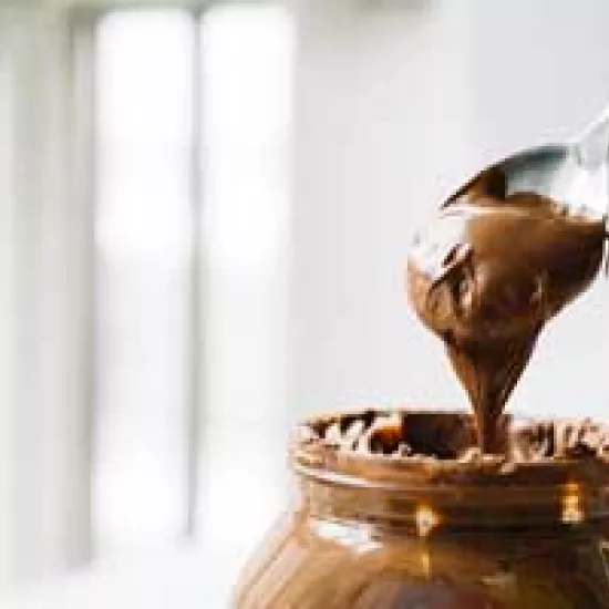 Photo of a jar and a spoon heaped with chocolate spread.