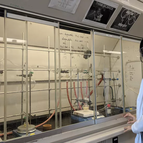 Woman standing in science lab, wearing lab coat and goggles