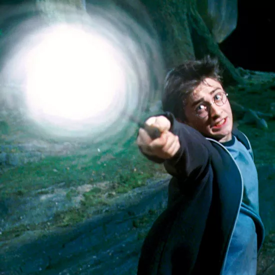 Movie still showing frightened Harry Potter casting a spell. The tip of his wand is engulfed in a swirling white light.