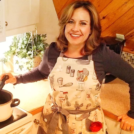 Kimberly Green in front of a stove and counter in a home kitchen, with a pot on the stove