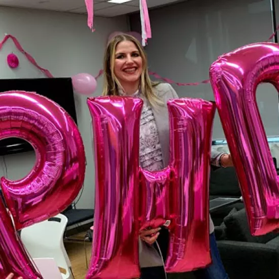 Sasha Weiditch holds pink balloons spelling out "P H D"