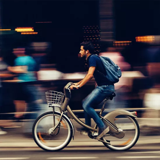 A man bikes along a busy city street.