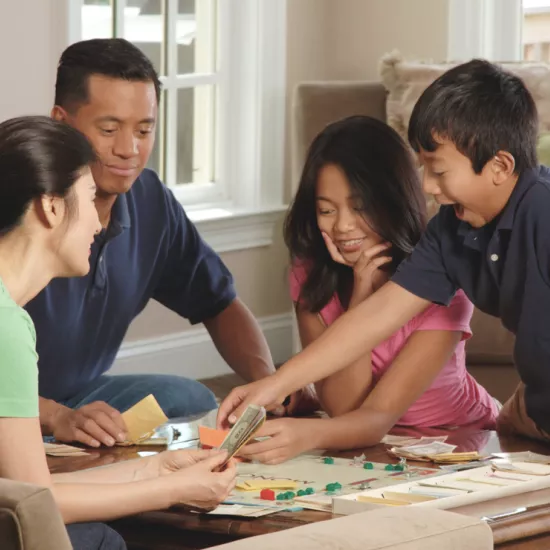 Family of four playing Monopoly together
