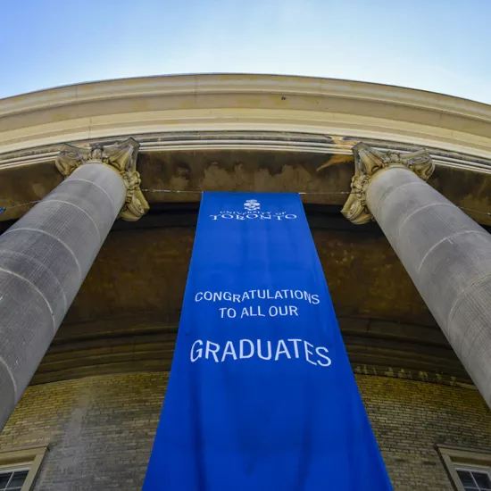 Looking up at convocation hall columns outside, blue banner reads: University of Toronto. Congratulations to all our graduates.