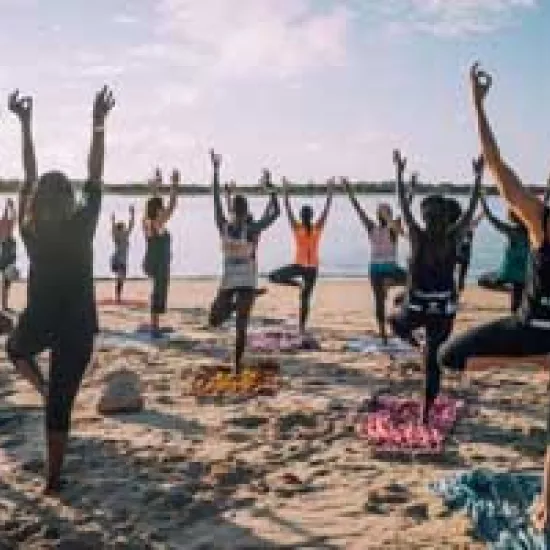 A group of people practice yoga on a beach.
