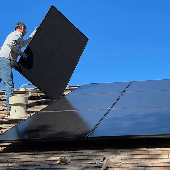 A man stands on a roof installing solar panels