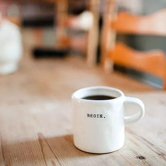 Coffee cup on table that reads "Begin"