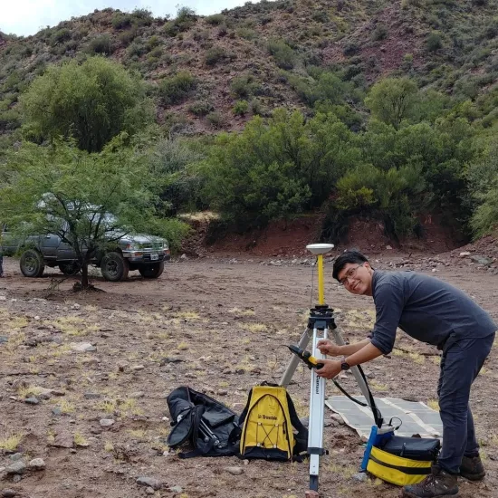 Jeremy Rimando sets up survey equipment in a rocky landscape.