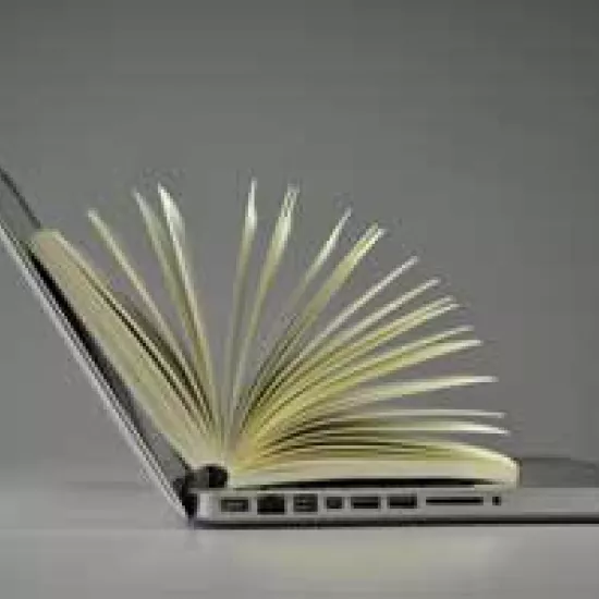 Open book balanced on the keyboard of an open laptop computer