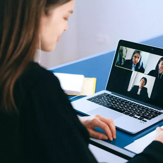 Woman in front of laptop on video call with three others shown on screen