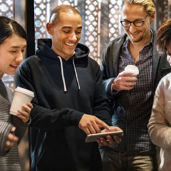 A group of college students smile as they look at a mobile phone.