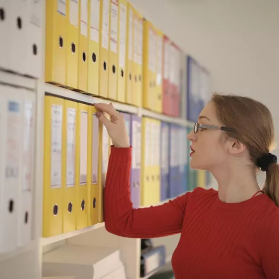 woman looking at index cards in front of index card filing cabinet