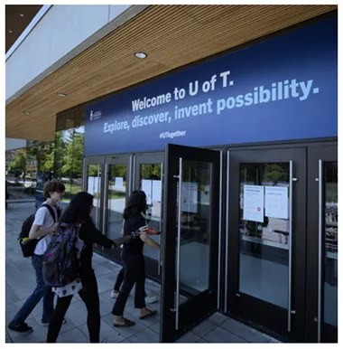 Students entering a U of T building. The signage reads, "Welcome to U of T. Explore, discover, invent possibility."