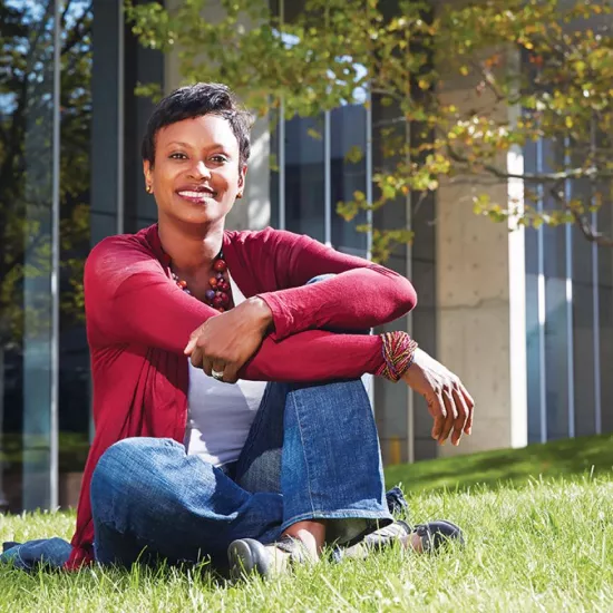 Rhonda McEwen seated on grass on the UTM campus