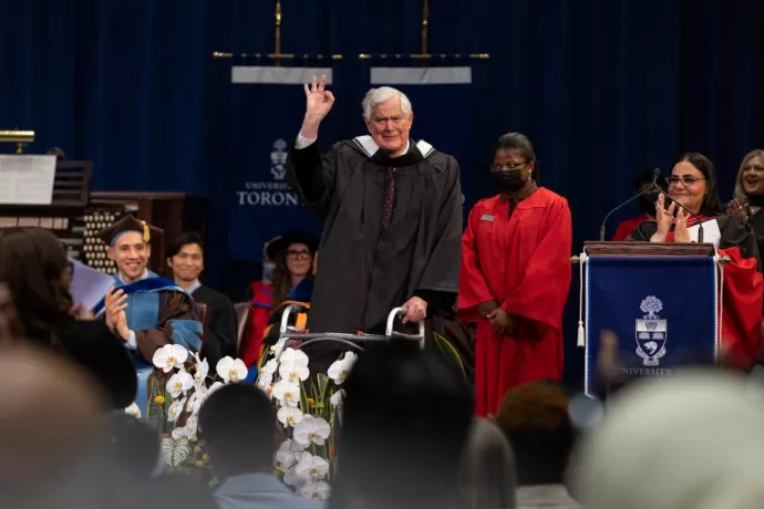 John Bond flashes an "okay sign" as he walks across the stage during Convocation 