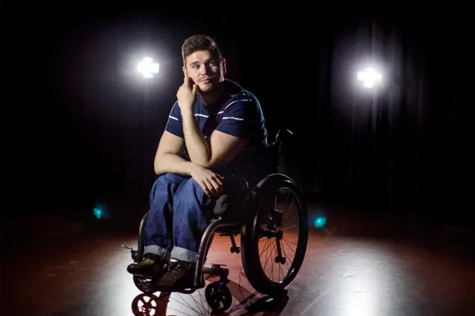 George Alevizos sitting in a wheelchair on center stage