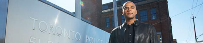 Professor Owusu-Bempah standing beside the Toronto Police sign