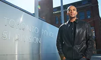 Photo of Professor Owusu-Bempah standing beside the Toronto Police sign
