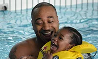 Man and toddler smiling in pool