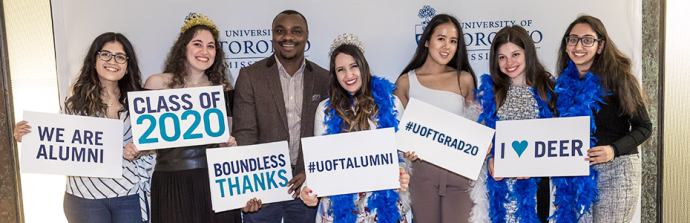 Group of graduates smiling and holding UTM signs